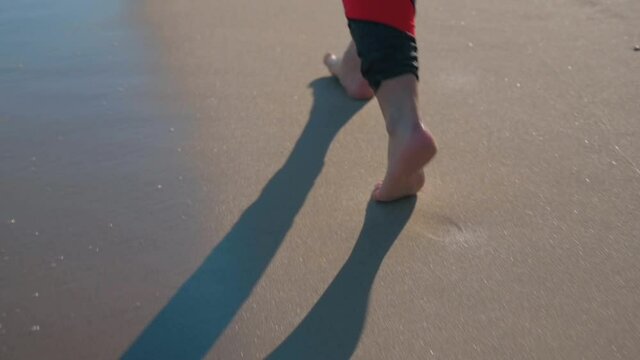 Barefoot woman legs walking on sand beach. Girl spending time near sea shore after running.
