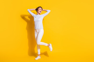 Fototapeta na wymiar Full length photo of cute shiny young woman wear white shirt dancing looking empty space isolated yellow color background