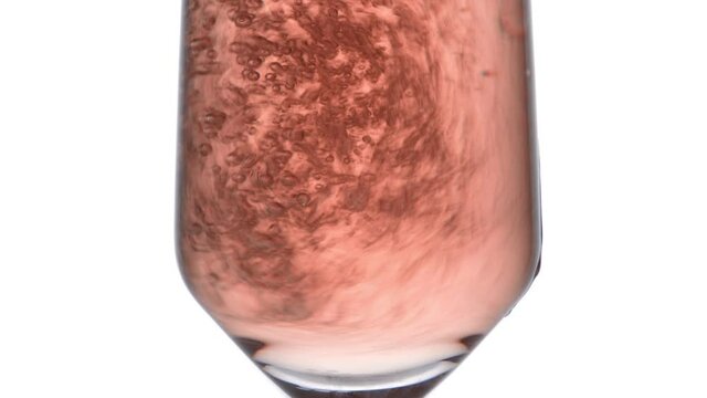 Closeup of glass with sparkling rose wine decorated gold star confetti, celebration party on white background