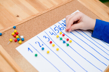 Little child doing simple math exercises. Early education, counting game. Preschool exercise for kids. Child learn to count to ten. Montessori math tool. 
