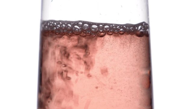 Closeup of glass with sparkling rose wine decorated gold star confetti, celebration party on white background