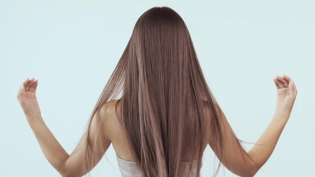 Woman moves long hair. Rear view. Girl shakes long straight hair. Female model is fluttering hair.   Slow motion footage. Rear view. Ginger. Red haired.