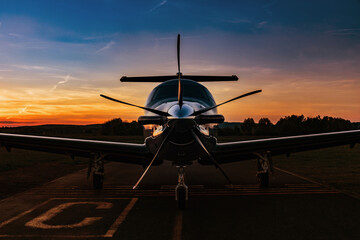A single-engine plane is parked on the runway, bathed in the evening sun. Beautiful color view of...