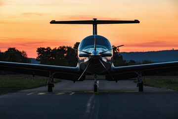 A single-engine plane is parked on the runway, bathed in the evening sun. Beautiful color view of...