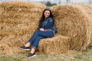 Naklejka na ściany i meble girl on sheaves of hay in summer with dark hair beautiful