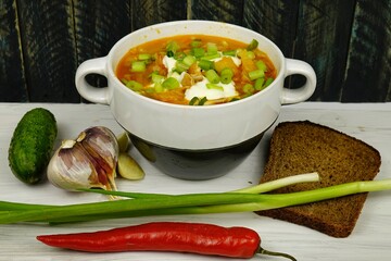 White plate with freshly prepared ukrainian borsch stands on the table against the background of a wooden board