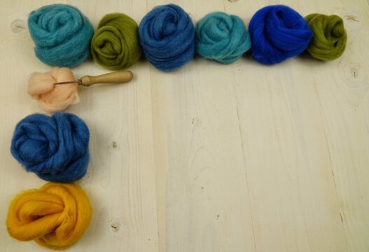 Skeins of multicolored yarn for felting lies on a white wooden board