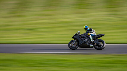 Fototapeta na wymiar A panning shot of a racing motorbike as it circuits a track.