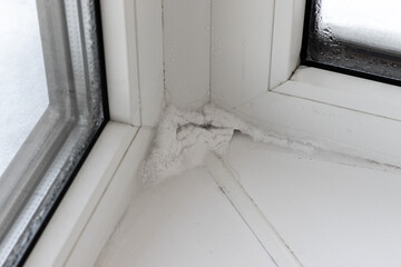 Ice, snow and condensate inside in corner of plastic window in winter. Poor warm isolation concept. Consequences of incorrect installation of window frames. Selective focus