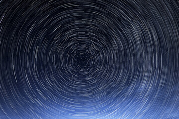 Stellar trails, the rotation of bright stars at night around the Polar Star against a blue sky and...