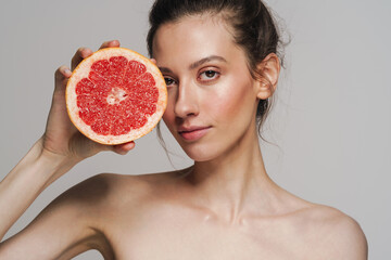 Pleased half-naked young woman posing with grapefruit