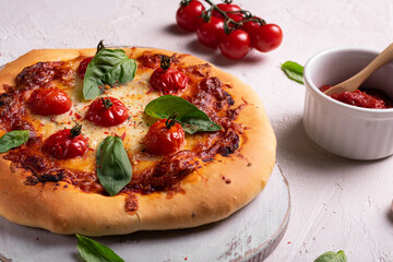 Homemade pizza with tomato and basil on a white board