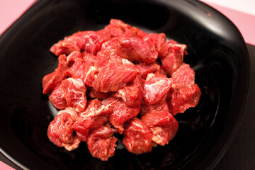 pork chopped into small pieces in a black plate on a bright colored background