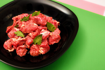 pork chopped into small pieces in a black plate on a bright colored background