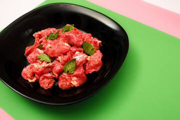 pork chopped into small pieces in a black plate on a bright colored background