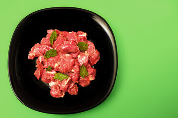 pork chopped into small pieces in a black plate on a bright colored background