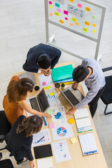 Group of four businesspeople working around desk and discuss for business plan graph and chart together in office. Take form top-down angle - 412929953