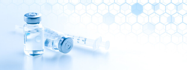 Medical syringe with a needle and a bollte with vaccine.