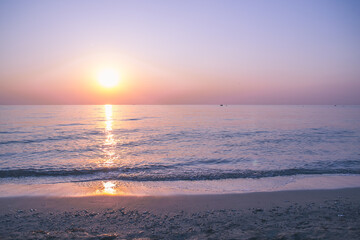 The sun rises on the sea coast. Calm water. Pink-lilac dawn. - 412932718