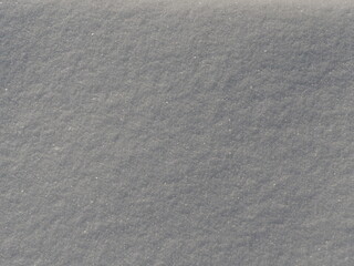 Frisch gefallener weißer Schnee auf einer ebenen Fläche im Sonnenlicht