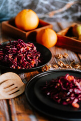 Red cabbage salad (coleslaw) with apples, oranges and walnuts on a dark wooden background, food still life