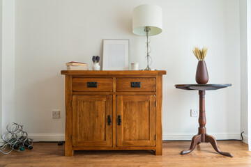 dining room interior of oak side board with  mock up silver picture frame, books, lamp and china...