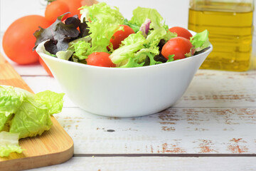 Mixed salad, accompanied by small tomatoes. Healthy contour. Copy space.