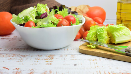 Mixed salad, accompanied by small tomatoes. Healthy contour. Copy space.