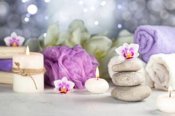 Fototapeta na wymiar Stones, burning candles, towel, abstract lights. Spa resort therapy composition.