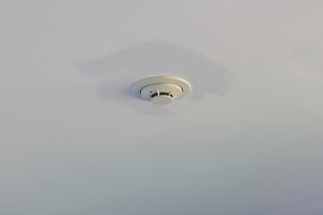 Smoke detector on white ceiling. Close up of smoke detector for fire protection systems. Selective focus.