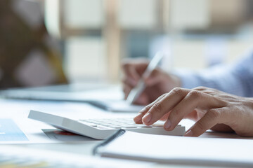 Close up Business man using calculator and laptop for do math finance on wooden desk, tax, accounting, statistics and analytical research concept