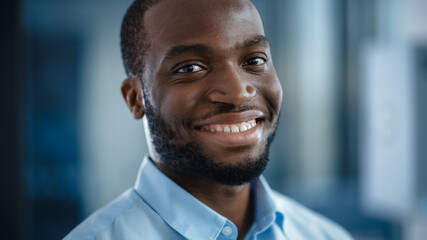 Close Up Portrait of a Black African American Handsome Male in a Light Blue Casual Shirt. Successful Man Calmly Smiles while Looking at Camera. Happy Stylish Businessman or a Doctor in Hospital.