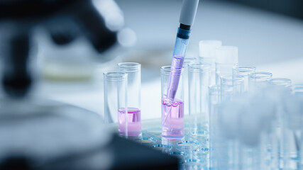 Close Up Shot of a Scientist Using Micro Pipette and Mixing Chemical Liquid with Genetically Modified Samples Under a Microscope. Microbiologist Working in Laboratory with Technological Equipment.