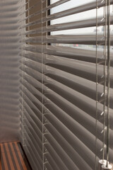 Aluminum blinds on the office windows. Made from metal. Venetian blinds closeup on the window. Silver color. Closed horizontal blinds in sunny day. Modern sun protection and window decoration.