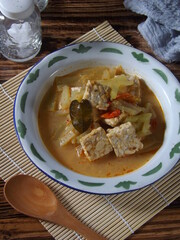 View of sayur lodeh or vegetables with coconut milk soup served in enamel plate. It is very popular Indonesian culinary food from Java, which made with chayote, tempe or tempeh, herbs, and spices.