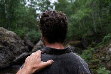 Young man turning around. a hand on a shoulder. guy in the dark forest.