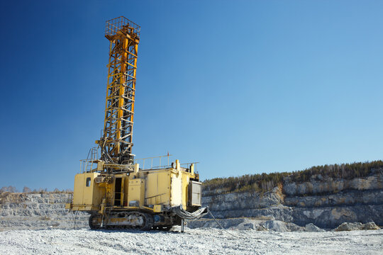 Mining drilling rig in a limestone quarry on the background of blue sky. Mining machinery. - Powered by Adobe