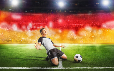 Ball on the green field in soccer stadium. Professional german Soccer Player Does Knee Slide...