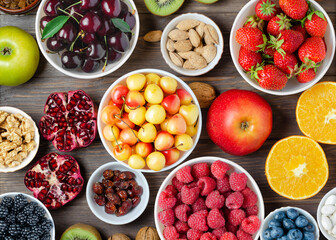 Mix of fresh berries, nuts and fruits. Healthy food contains a lot of vitamins and useful trace elements. Brown wooden background.