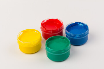 Plastic jars with paint of different colors for children's creativity on white background. Paint bottles for art