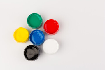 Plastic jars with paint of different colors for children's creativity on white background. Paint bottles for art