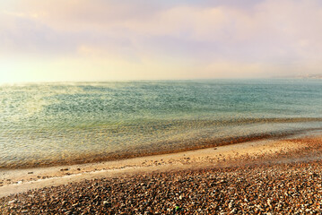Calm seascape. Water and a deserted beach in small pebbles. 