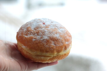 Closeup of a traditional Polish donut with snow in the background. Concept of the tradition of Fat Thursday celebrated in Poland.