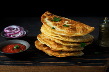 Homemade fried empanadas with pork, chebureks with mushrooms on a wooden