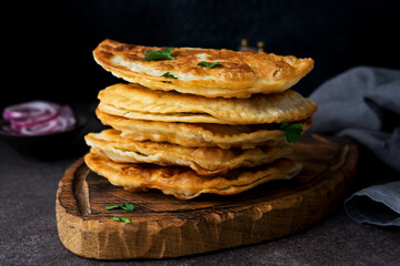 Homemade fried empanadas with pork, chebureks with mushrooms on a wooden