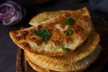 Homemade fried empanadas with pork, chebureks with mushrooms on a wooden