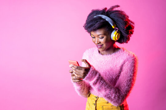 Young beautiful black woman texting smartphone listening music