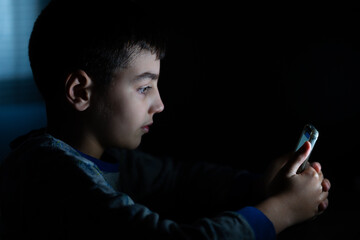 child using mobile phone in dimly lit room
