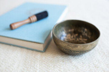 Singing bowl or tibetan bowl and wooden mallet or stick for meditation, mindfulness, sound healing, relaxation. With a book.