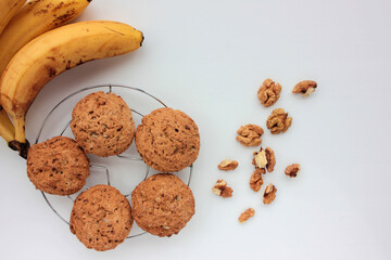 Oatmeal banana cookies with nuts on white table. Overhead view of oat biscuits, walnuts and yellow fruits on white background with copy space